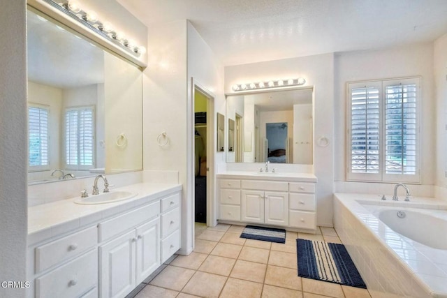 bathroom featuring vanity, tile patterned flooring, and tiled tub