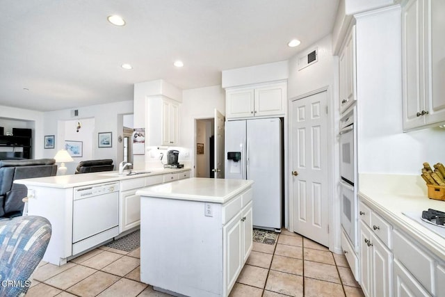 kitchen featuring light tile patterned flooring, white appliances, a kitchen island, and white cabinets