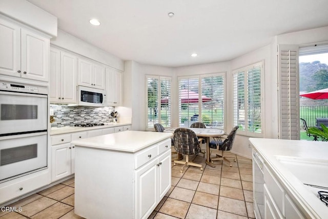 kitchen with white cabinetry, white appliances, decorative backsplash, and a kitchen island