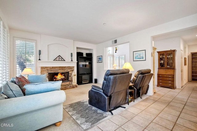 tiled living room with a stone fireplace