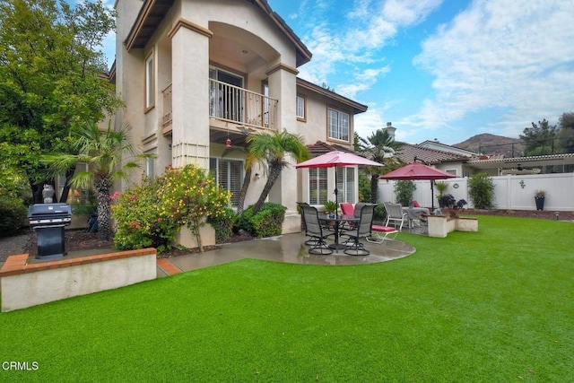 back of property featuring a balcony, a yard, and a patio area