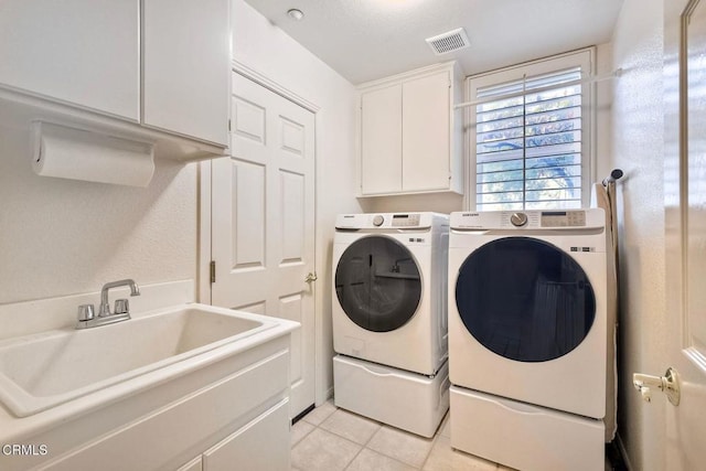 washroom featuring sink, light tile patterned floors, washing machine and dryer, and cabinets