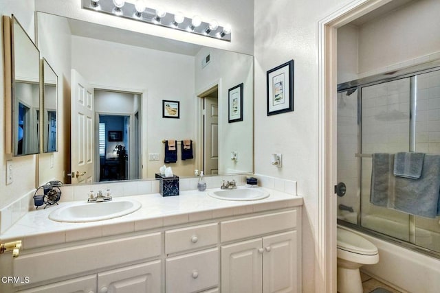 full bathroom with vanity, toilet, and combined bath / shower with glass door