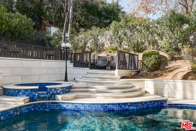 view of swimming pool with an in ground hot tub