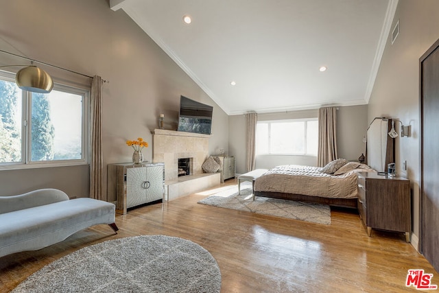 bedroom with a fireplace, crown molding, light hardwood / wood-style floors, and vaulted ceiling with beams