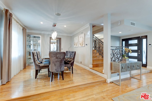 dining area with ornamental molding and light hardwood / wood-style floors