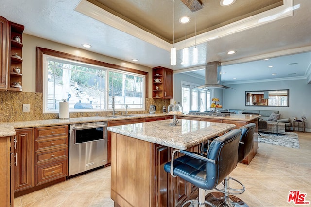 kitchen featuring a breakfast bar area, appliances with stainless steel finishes, a raised ceiling, ornamental molding, and a center island