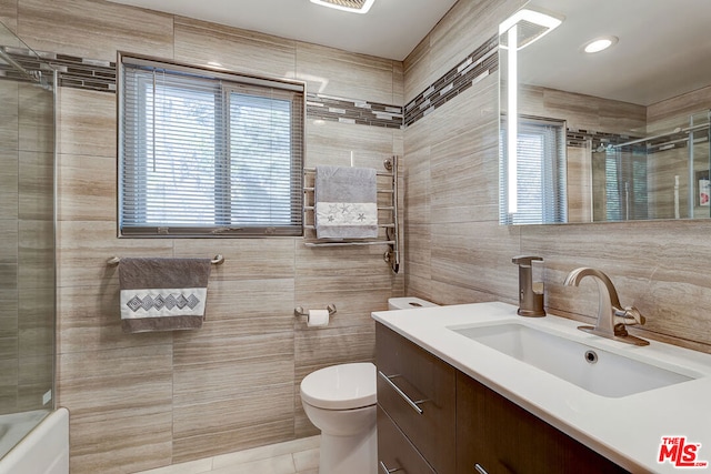 bathroom featuring toilet, tile patterned flooring, tile walls, and vanity