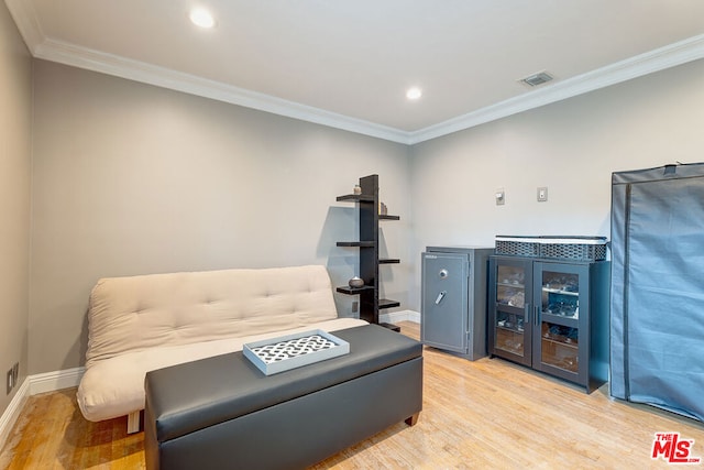 living area featuring crown molding and light hardwood / wood-style floors