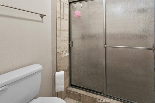 bathroom featuring a shower with shower door and toilet