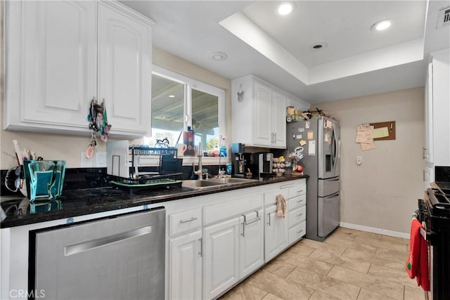 kitchen with a raised ceiling, appliances with stainless steel finishes, and white cabinetry