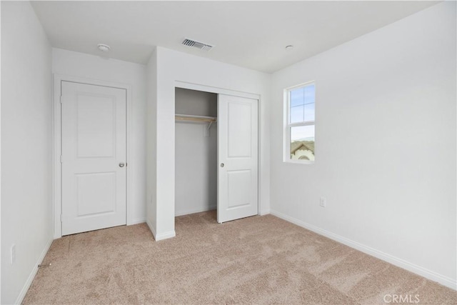 unfurnished bedroom featuring light carpet and a closet