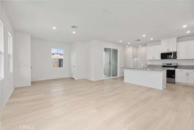 kitchen with light hardwood / wood-style floors, a kitchen island with sink, light stone countertops, stainless steel appliances, and white cabinets