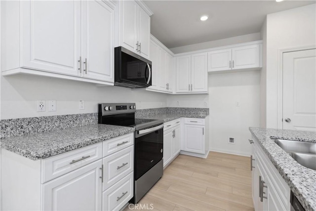 kitchen with light stone counters, white cabinets, and stainless steel appliances