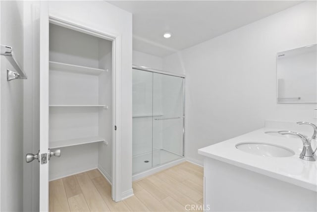 bathroom featuring a shower with shower door and vanity