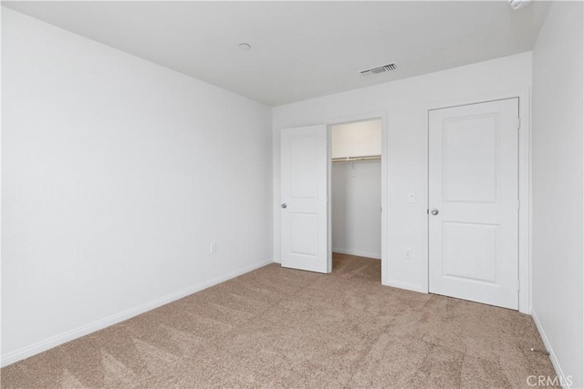 unfurnished bedroom featuring light carpet and a closet