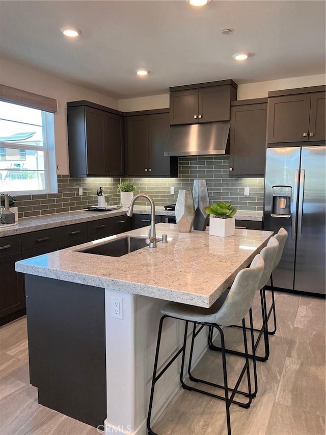 kitchen with stainless steel fridge with ice dispenser, a breakfast bar area, sink, and a kitchen island with sink