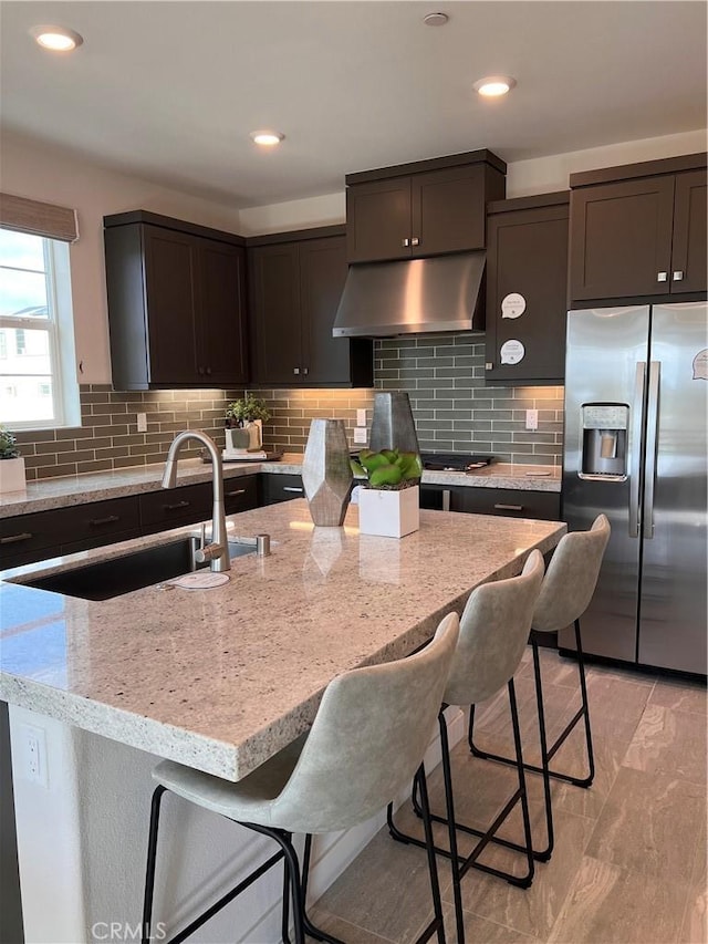 kitchen featuring a kitchen island with sink, appliances with stainless steel finishes, sink, and a breakfast bar area