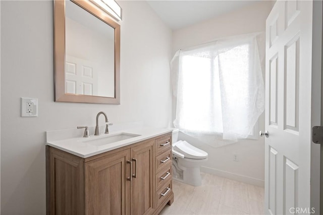 bathroom featuring vanity, toilet, and baseboards