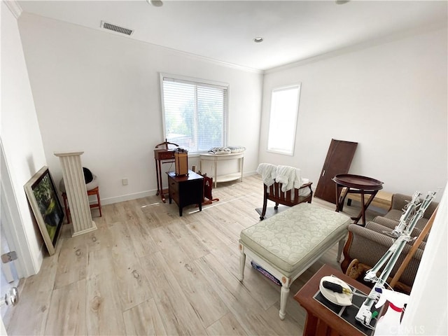 living area with light wood-type flooring, baseboards, visible vents, and crown molding