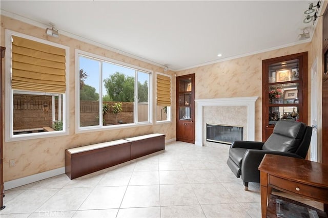 living area with baseboards, ornamental molding, and wallpapered walls