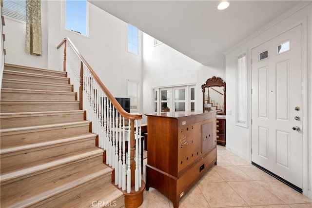 foyer entrance featuring stairway, a high ceiling, and light tile patterned floors