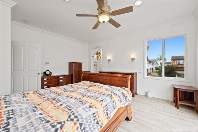 bedroom featuring baseboards, crown molding, light wood finished floors, and ceiling fan