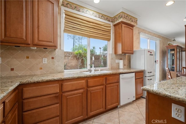 kitchen featuring crown molding, white appliances, a sink, and light stone counters