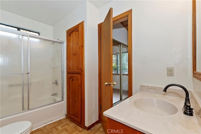 full bathroom with parquet flooring, bath / shower combo with glass door, toilet, and vanity