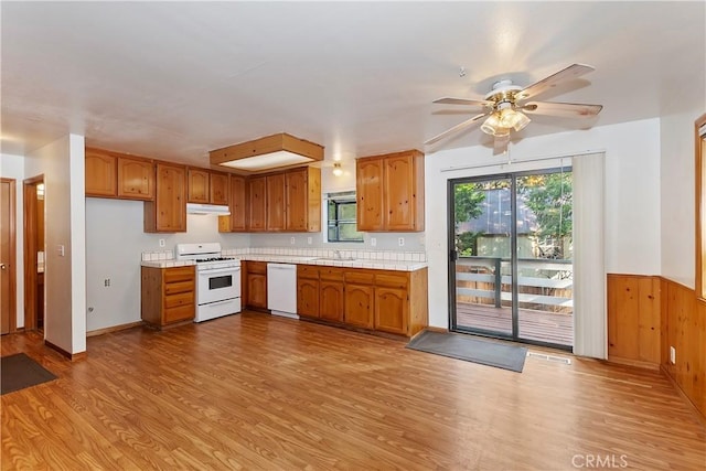 kitchen featuring ceiling fan, sink, white appliances, wood walls, and light hardwood / wood-style floors