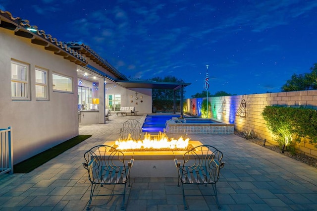 pool at twilight featuring pool water feature, an outdoor fire pit, and a patio area