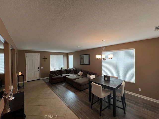 dining area featuring a textured ceiling, a chandelier, and tile patterned flooring