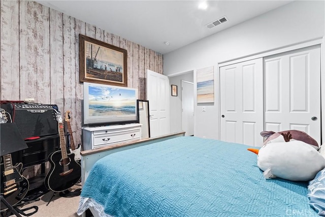 carpeted bedroom featuring a closet and wood walls