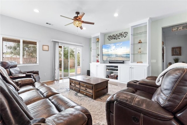 living room with ceiling fan, light hardwood / wood-style floors, and built in shelves