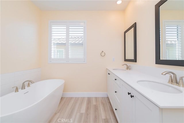 bathroom featuring a healthy amount of sunlight, a bathtub, wood-type flooring, and vanity