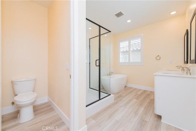 full bathroom with hardwood / wood-style flooring, toilet, vanity, and independent shower and bath