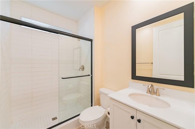 bathroom featuring toilet, a shower with shower door, and vanity