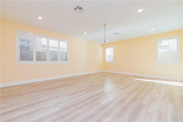 empty room with plenty of natural light and light hardwood / wood-style floors