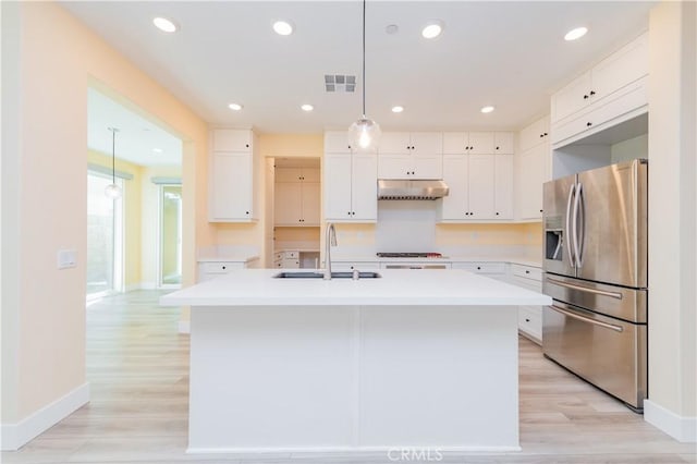 kitchen featuring stainless steel refrigerator with ice dispenser, white cabinets, a center island with sink, and sink