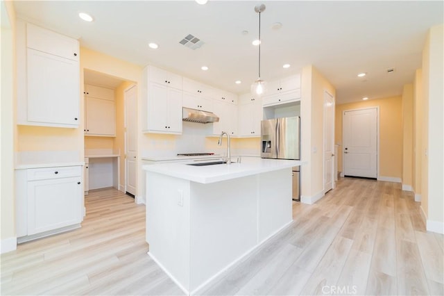 kitchen featuring light hardwood / wood-style floors, an island with sink, decorative light fixtures, white cabinets, and sink