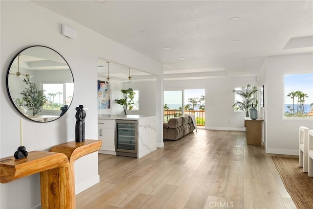 interior space with light wood-type flooring, indoor bar, and beverage cooler