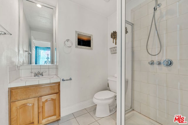 bathroom featuring toilet, vanity, a shower with door, and tile patterned floors