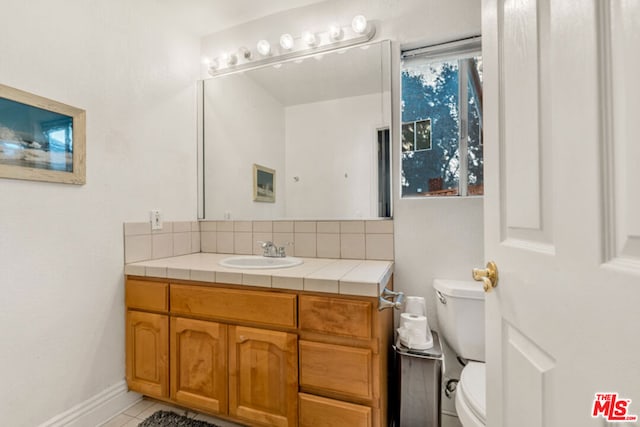 bathroom featuring tile patterned floors, vanity, toilet, and tasteful backsplash