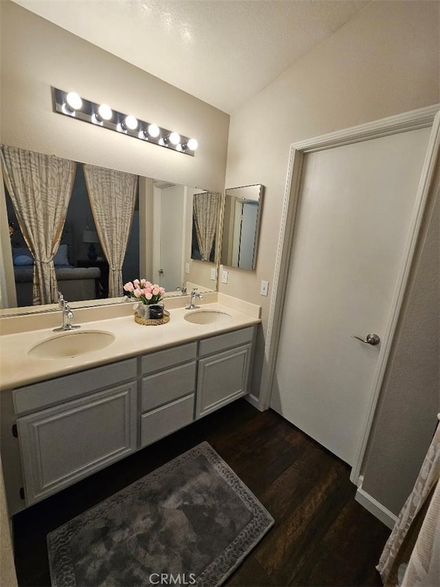 bathroom with hardwood / wood-style floors, vanity, and lofted ceiling