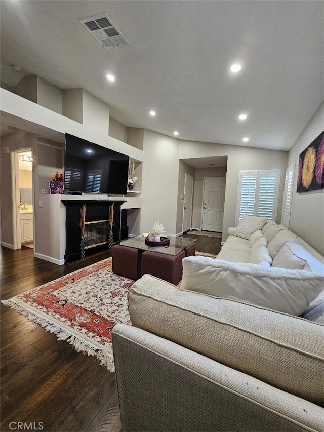 living room with lofted ceiling, built in shelves, and dark hardwood / wood-style flooring