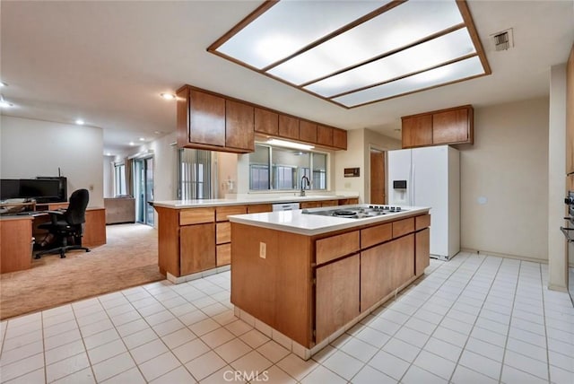 kitchen with white appliances, a kitchen island, sink, kitchen peninsula, and light colored carpet