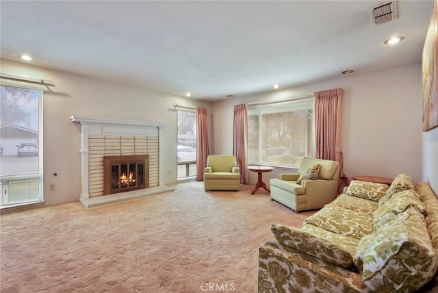 living room featuring carpet floors, a healthy amount of sunlight, and a fireplace