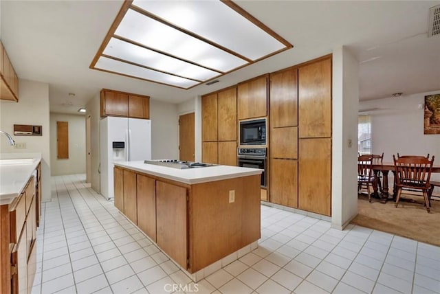 kitchen with black appliances, light tile patterned floors, sink, and a center island