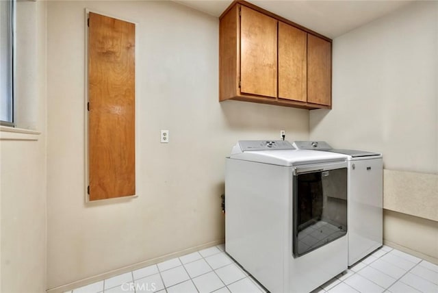 laundry area with light tile patterned floors, washer and dryer, and cabinets