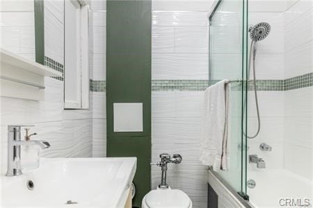 full bathroom featuring toilet, shower / bath combination with glass door, and sink